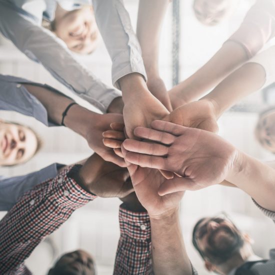 Close up view of young business people putting their hands together. Stack of hands. Unity and teamwork concept.